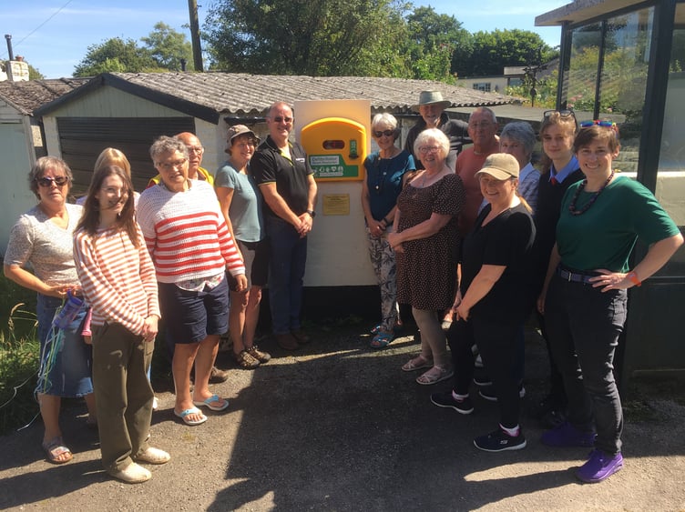 Local residents from Higher Tremarcoombe proudly stand by the new defibrillator they have secured for the hamlet